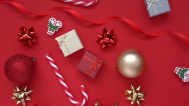 Noel arkaplanı. 4k Döndürme Videosu hediye kutusu, köknar ağacı dalları ve birçok Xmas çizgili şeker, kırmızı arka planda kırmızı şenlik süslemeleri. Noel ve yeni yıl tatili konsepti