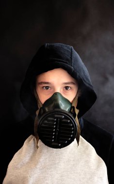 Siyah arka planda gaz maskeli bir genç.