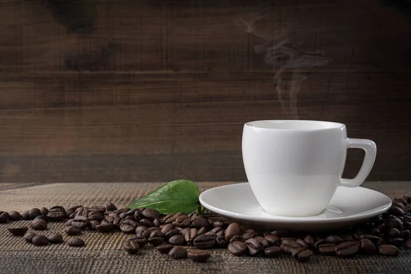 Masanın üzerinde bir fincan kahve ve fasulye var. Siyah arkaplan