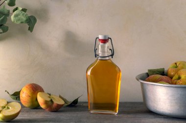 Taze elmalar ve elma sirkesi. Cam şişede elma şarabı ve taze elmalar. Hafif arkaplan.