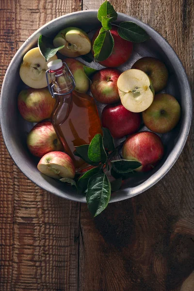 Fresh ripe apples and apple cider vinegar. Apple cider in a glass bottle and fresh apples on an old wooden table. Dark background. Top view.