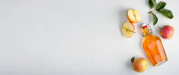 Taze elmalar ve elma sirkesi. Cam şişede elma şarabı ve taze elmalar. Hafif arkaplan. Üst Manzara. Pankart. Metninizin alanını kopyala.