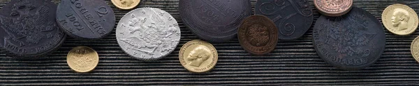 Numismatikler. Tahta bir masanın üzerinde gümüş, altın ve bakırdan yapılmış eski koleksiyon paraları. Üst Manzara. Pankart.