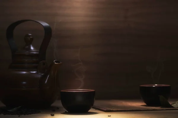 Asian tea set and tea leaves on a wooden table. Dark background. Tea concept.