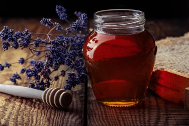 Taze lavanta balı, bal petekleri ve lavanta çiçekleri eski ahşap bir masada. Koyu arkaplan.