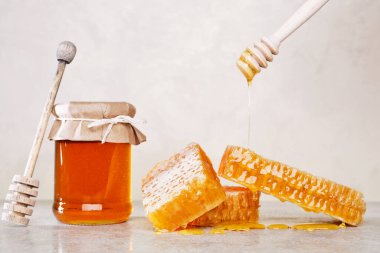 Bal geçmişi. Tarakta tatlı bal, cam kavanoz ve masada bal için bir kaşık. Hafif arkaplan.
