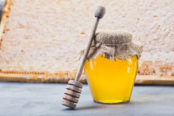 Honey background. Sweet honey in the comb, glass jar. On wooden background