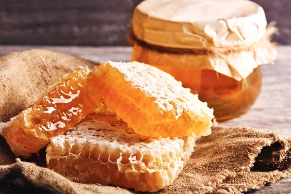 Bal geçmişi. Tarakta tatlı bal, cam kavanoz. Ahşap arka planda