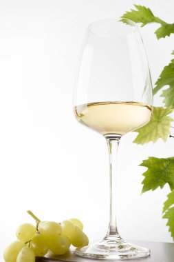Bardakta beyaz şarap ve masada bir demet üzüm. Hafif arkaplan.