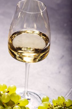 Masada bir bardak beyaz şarap ve taze üzüm..
