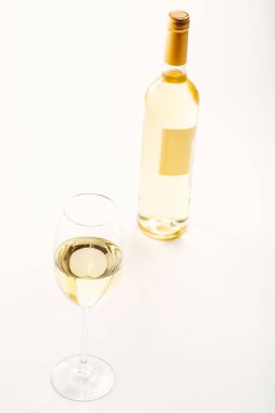 Bir bardak beyaz şarap ve bir şişe. Beyaz arkaplan
