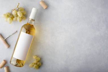 Üzerinde etiket, üzüm, mantar ve şişe açacağı olan bir şişe beyaz şarap. Üst görünüm.
