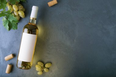 Üzerinde etiket, üzüm, mantar ve şişe açacağı olan bir şişe beyaz şarap. Üst görünüm.