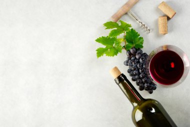 Bir bardak kırmızı şarap, üzüm ve üzüm masada şarap şişesi ve mantar bırakır. Metniniz için metin alanı olan üst görünüm.