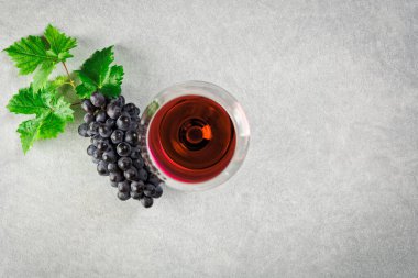 Masada kırmızı şarap ve bir demet üzümlü bir bardak var. Yukarıdan görüntüle