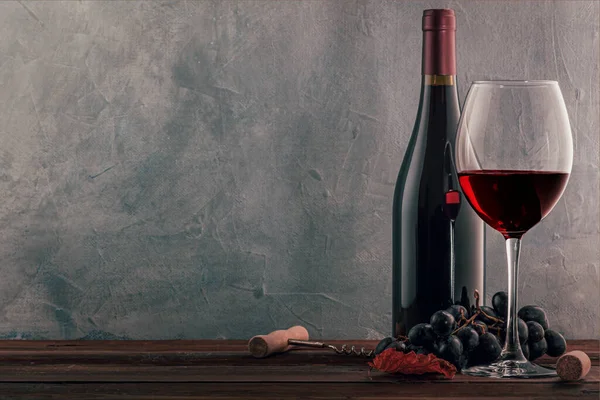 古い木製のテーブルの上に赤ワイン ボトル コルク オープナーとブドウのガラス — ストック写真