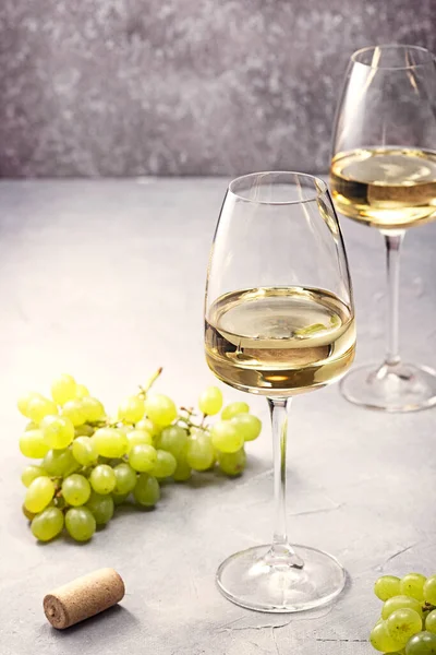A glass of white wine and fresh grapes on the table.