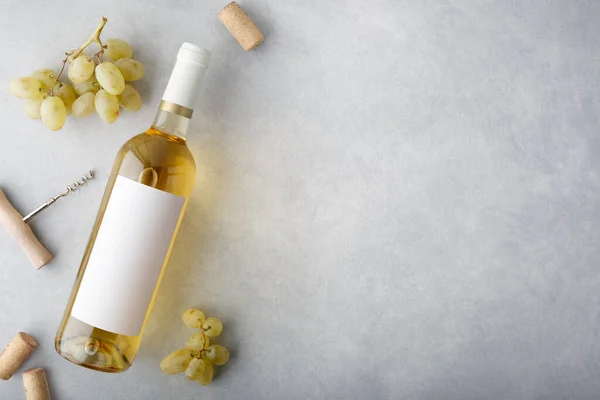 Üzerinde etiket, üzüm, mantar ve şişe açacağı olan bir şişe beyaz şarap. Üst görünüm.