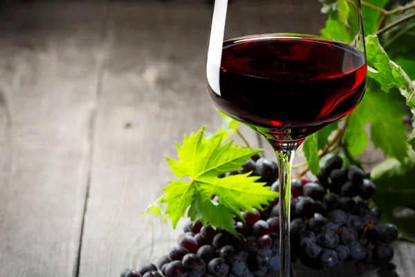 Kırmızı şarap ve üzüm. Şarap ve üzümler, ahşap masa mantarlı eski usul.