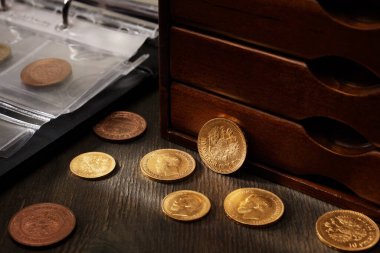 Numismatikler. Tahta bir masanın üzerinde gümüş, altın ve bakırdan yapılmış eski koleksiyon paraları.. 