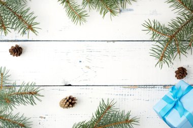 Noel kompozisyonu. Noel hediyesi, çam kozalakları, tahta beyaz arka planda köknar dalları. Düz konum, üst görünüm, kopyalama alanı