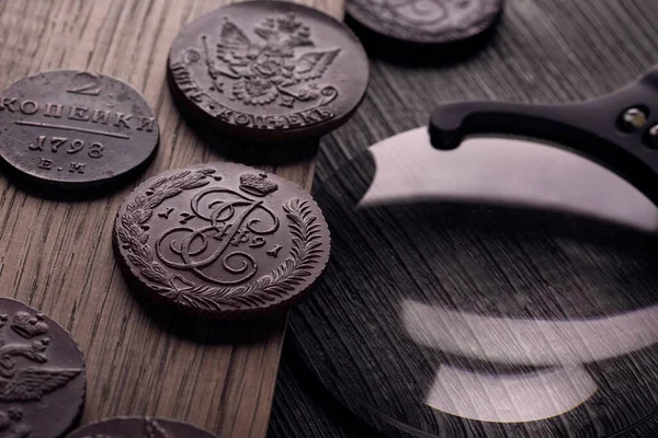 Numismatikler, eski paraları toplamak. Çarlık Rusya 'sının sikkeleri ve masada bir büyüteç.