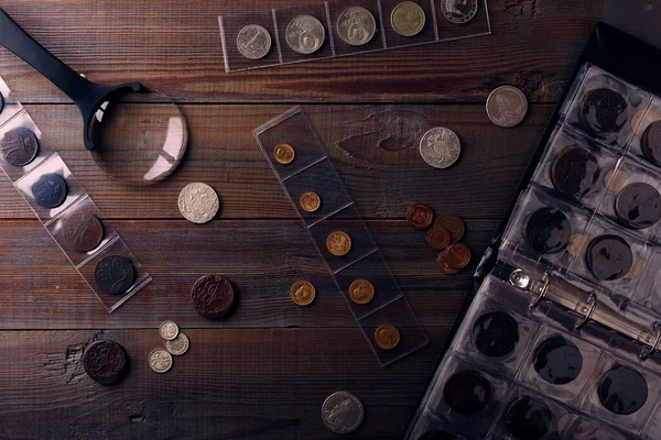 Numismatikler. Tahta bir masanın üzerinde gümüş, altın ve bakırdan yapılmış eski koleksiyon paraları. Üst görünüm.