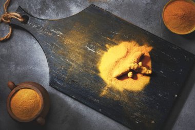 Zerdeçal tozu ve ahşap arka planda taze zerdeçal. Karanlık arka plan. Üst görünüm.