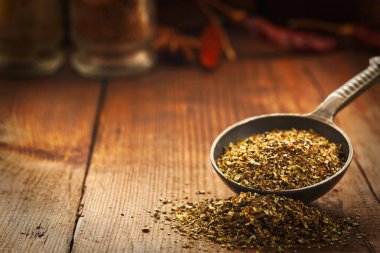 Marjoram yaprakları bir ölçü kaşığından dökülüyor. Arkaplan