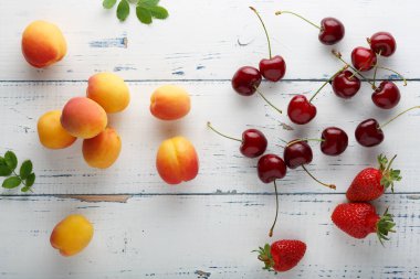 Olgun lezzetli kayısı, tatlı kiraz, masaya saçılmış çilek. Üst görünüm