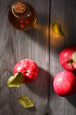Eski ahşap bir masada taze olgun elmalar ve elma sirkesi. Karanlık arka plan. Üst görünüm.