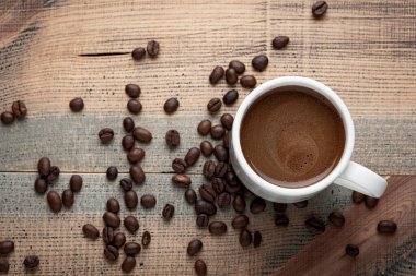 Masanın üzerinde bir fincan kahve ve fasulye var. Karanlık arka plan. Üst görünüm.