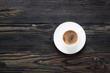 Eski ahşap bir masada beyaz bir fincanda taze ve aromatik kahve. Üst görünüm