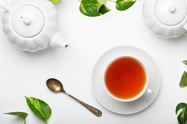 Taze demlenmiş çay, çaydanlık, hafif bir masada şeker kasesi. Beyaz tabaklar. Beyaz arka plan. Üst görünüm.