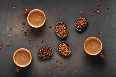 Masanın üzerinde taze ve aromatik kahve ve kahve çekirdekleri olan üç fincan. Üst görünüm.
