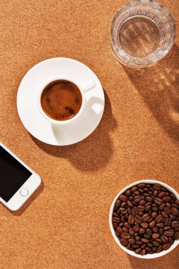Masanın üzerinde bir fincan kahve ve fasulye var. Parlak güneş ışığı. Üst görünüm