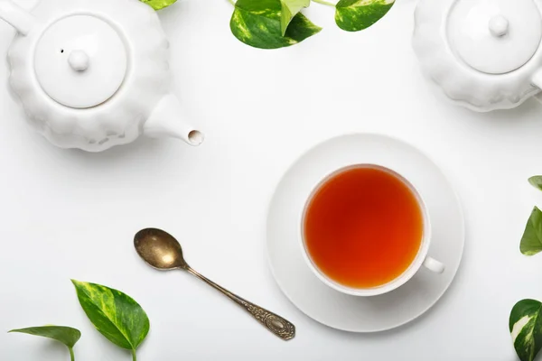 Taze demlenmiş çay, çaydanlık, hafif bir masada şeker kasesi. Beyaz tabaklar. Beyaz arka plan. Üst görünüm.