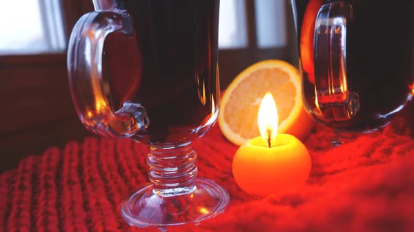 Mulled wine in glass mugs, burning candle on a dark red background. Red Hot wine — Stock Photo, Image