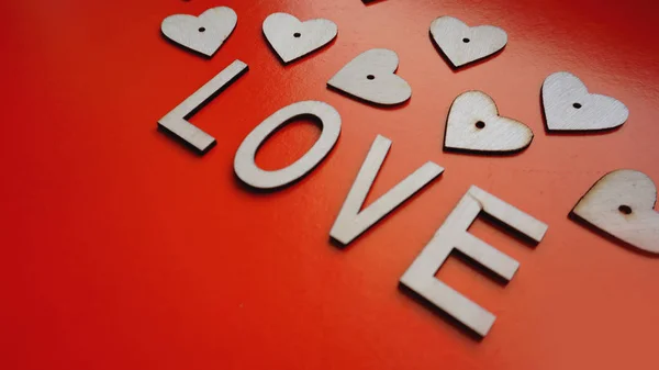 El fondo de San Valentín con los corazones rojos y las letras el amor - hecho de madera sobre rojo —  Fotos de Stock