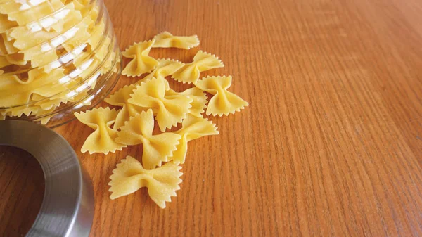 Pasta en forma de arcos esparcidos del frasco de vidrio. Pastas italianas hechas a mano —  Fotos de Stock