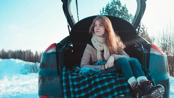Счастливая девушка сидит на грузовике автомобиля в зимнем лесу — стоковое фото