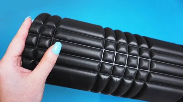 Foam Roller Gym Fitness Equipment Blue background self Myofascial Release - MFR. Hand holds a roller. How to choose equipment for sports