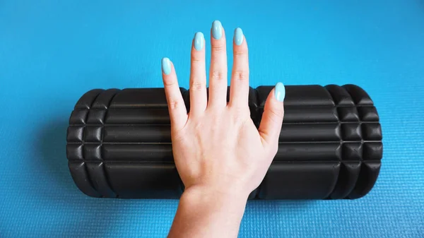 Foam Roller Gym Fitness Equipment Blue background self Myofascial Release - MFR. Hand holds a roller. How to choose equipment for sports — Stock Image Foam Roller Gym Fitness Equipment Blue Background Self Myofascial Release Royalty Free Stock Photos