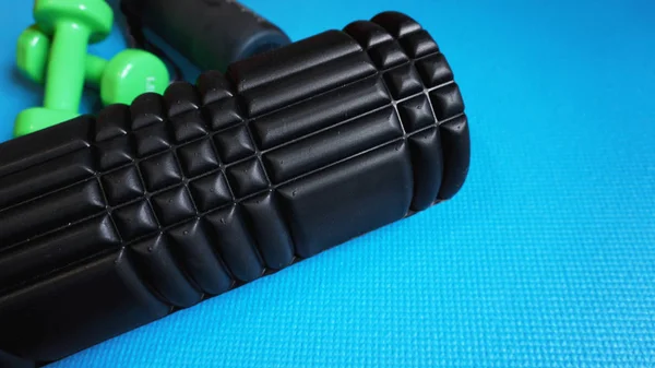 Foam Roller with green dumbbells Gym Fitness Equipment Blue background self Myofascial Release - MFR. — Stock Image Foam Roller Green Dumbbells Gym Fitness Equipment Blue Background Self Royalty Free Stock Images