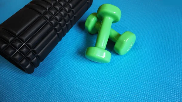 Foam Roller with green dumbbells Gym Fitness Equipment Blue background self Myofascial Release - MFR. — Stock Image Foam Roller Green Dumbbells Gym Fitness Equipment Blue Background Self Stock Picture