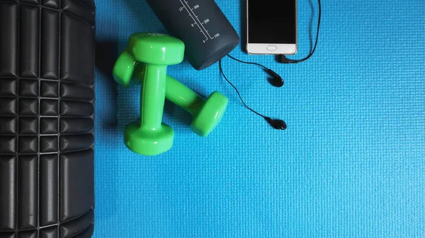 Foam Roller with green dumbbells and water bottle and telephone with headphones - Gym Fitness Equipment Blue background self Myofascial Release - MFR. — Stock Image Foam Roller Green Dumbbells Water Bottle Telephone Headphones Gym Fitness Stock Picture