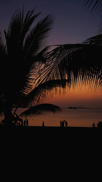 Silueta de personas en la playa tropical al atardecer - Turistas disfrutando del tiempo — Foto de Stock