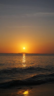 Denizin altında parlak gün batımı, sarı kırmızı renkler.