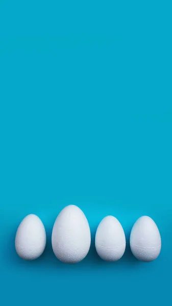 White foam eggs on blue background. Flat lay, top view. Easter concept
