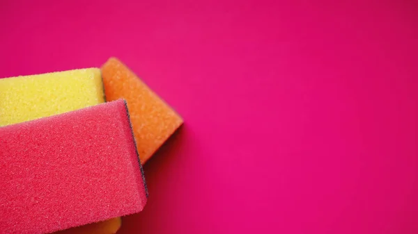 Household cleaning concept. Colorful sponges on pink background